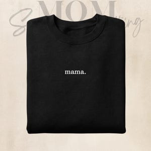 Könnte beinhalten: Schwarzes Sweatshirt mit Rundhalsausschnitt und dem Wort "mama." in Weiß, mittig auf der Brust. Das Sweatshirt hat eine einfarbige schwarze Farbe, und der Text ist in einer einfachen, serifenlosen Schriftart. Das Sweatshirt ist ein lässiger Stil.