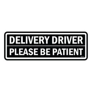 May include: A black and white rectangular sign with the words "DELIVERY DRIVER PLEASE BE PATIENT". The sign has a white border and is designed for clear visibility. The text is in a bold, sans-serif font.