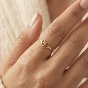 May include: A thin gold ring featuring a small heart-shaped charm and a letter C charm attached to the band. The metal has a polished finish, and the two charms are positioned side-by-side on the top of the ring, creating a delicate and simple design.
Custom Cursive Initial Ring, 14K Solid Gold, Romantic Script Jewelry