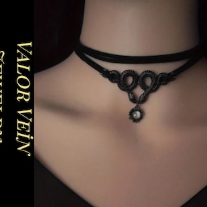 Puede incluir: Collar gargantilla negro con un colgante decorativo con un diseño en espiral y una pequeña gema blanca y redonda. El collar se lleva alrededor del cuello. El texto "VALOR VEIN JEWELRY" está en el lado izquierdo de la imagen.