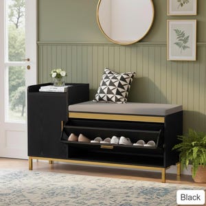 May include: Black shoe storage bench with a gray cushioned seat, gold accents, and two shoe compartments. The bench has a side cabinet and is placed against a green wall with a round mirror and decorative art.