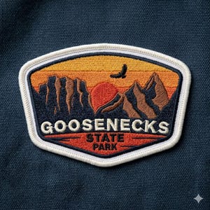May include: Embroidered patch featuring a sunset over mountains with a flying bird. The patch reads "Goosenecks State Park" in white lettering. The patch has a white border and is set against a navy blue background.