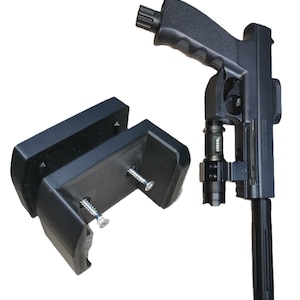 Puede incluir: Pistola negra con un accesorio de linterna y un soporte de montaje negro separado. La pistola tiene una empuñadura texturizada y una extensión de cañón cilíndrica. El soporte de montaje tiene dos tornillos para la fijación.