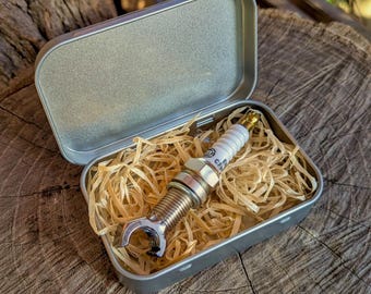 Handmade bottle opener made from a spark plug, packaged in a sturdy tin box as a gift.