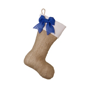May include: A festive Christmas stocking made from burlap, featuring a white cuff and a vibrant blue bow. The stocking has a loop for hanging. The natural, woven texture of the burlap contrasts with the bright bow.
