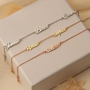 May include: Four name bracelets in silver, gold, and rose gold. Each bracelet features a different name: Jennie, Bella, Sophia, and Colleen. The bracelets are displayed on a white surface, showcasing their elegant design.