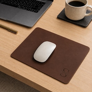 May include: A rectangular dark brown leather mouse pad featuring a smooth surface and rounded corners. The bottom right corner is embossed with a large letter S and the name Scott centered horizontally across the letter in a serif font.
