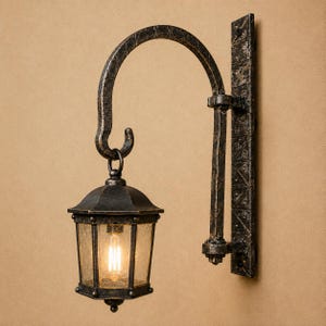 Peut inclure: Une applique murale en forme de lanterne avec une finition métallique bronze foncé vieilli. Elle se compose d'une plaque murale rectangulaire verticale, d'un bras de support incurvé avec des détails croisés et d'une lanterne hexagonale en verre.