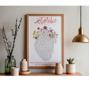 May include: A framed print with Arabic calligraphy and English text, featuring a heart-shaped illustration filled with text and adorned with colorful flowers. The print is in a light wood frame, displayed on a wooden surface with decorative items.