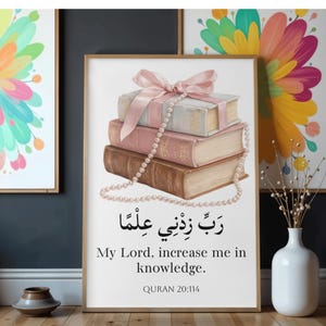 Op de afbeelding: Een ingelijste print met een stapel boeken, vastgebonden met een roze lint en versierd met een parelketting. De print bevat Arabische kalligrafie en de Engelse tekst "My Lord, increase me in knowledge." Koran 20:114.