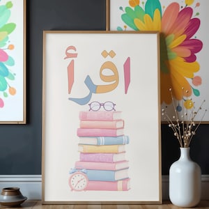 May include: A framed wall art print featuring a stack of pastel-colored books topped with purple reading glasses and a small pink alarm clock. Above the books, the Arabic word Iqra is written in large, colorful, stylized lettering.