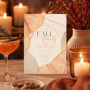 Op de afbeelding: Een rechthoekige uitnodigingskaart met een crèmekleurig midden, omlijst door grote, doorschijnende, bruine en beige gedroogde bladeren. De tekst luidt: You're invited to a FALL Party, Saturday September 21 at 8:00 PM, Good food, Warm drinks, Great company, Hosted by The Johnson Family, 123 Autumn Lane, Riverdale, CT 06475, RSVP to Julie by September 1st (555) 123-4567.