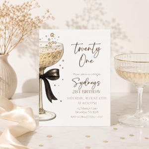 Op de afbeelding: Een uitnodiging voor een 21e verjaardag met een champagnethema. De uitnodiging toont een illustratie van een champagneglas met een zwarte strik en de woorden "Twenty One" in elegant schrift. De tekst bevat ook de naam "Sydney's", datum, tijd en locatie.
