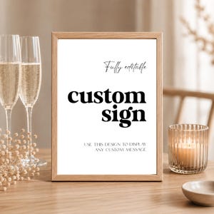 Op de afbeelding: Een rechthoekige houten lijst met een wit bord met zwarte tekst die luidt Fully editable, custom sign, en USE THIS DESIGN TO DISPLAY ANY CUSTOM MESSAGE. Het bord staat rechtop op een houten ondergrond.