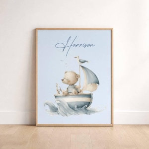 Puede incluir: Impresión en acuarela de un oso de peluche navegando en un barco sobre un fondo azul claro. El oso lleva una camisa a rayas y navega en un barco con una gaviota encima. El nombre "Harrison" está escrito en cursiva.