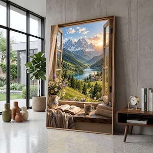 May include: A large rectangular wall art print depicting an open window view of a mountain landscape with a lake, a small village, and a sunset. The window sill features an open book, a ceramic mug, a vase of wildflowers, and a draped blanket.
