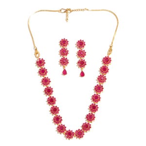 May include: A gold necklace and earring set with ruby-red floral designs. The necklace and earrings have a fine chain and are decorated with bright red gemstones. The earrings feature a teardrop-shaped gemstone at the bottom.