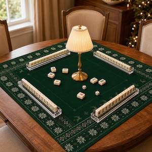Può includere: Un tappetino da gioco quadrato verde scuro con un bordo decorato da fiocchi di neve e renne bianche. Include quattro supporti per tessere in acrilico trasparente, tessere del mahjong color avorio, due dadi bianchi e una lampada in ottone.