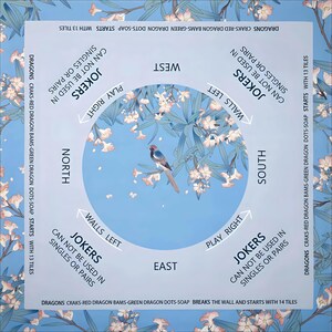 May include: A square Mahjong game mat featuring a light blue background with floral patterns. The center displays a bird on a branch. Text includes cardinal directions, play instructions, and rules regarding jokers, tiles, and wall breaks.