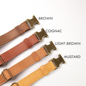 May include: Four leather straps with antique brass-toned metal buckles, arranged diagonally. The straps are labeled BROWN, COGNAC, LIGHT BROWN, and MUSTARD. Each strap features a matching leather loop and a rectangular metal adjustment slider.