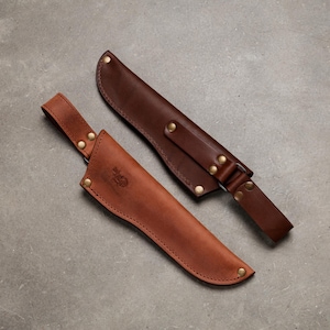 Peut inclure: Deux étuis à couteau en cuir marron avec des rivets en métal couleur laiton. L'étui marron clair présente un passant de ceinture et un logo estampé, tandis que l'étui marron foncé possède une sangle renforcée et une attache métallique.