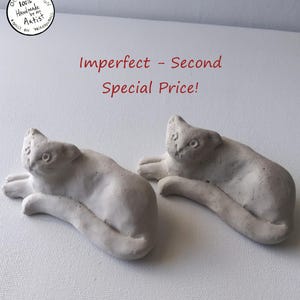 May include: Two off-white cat figurines in a relaxed pose. The text "Imperfect - Second Special Price!" is in red. The top left corner has a circular logo with text: "Original Design 100% Handmade by the Artist Only on Wireanimals."