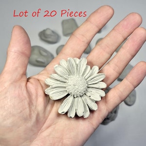 May include: A hand holding a gray, daisy-shaped decorative piece. The daisy has detailed petals and a textured center. The image includes the text "Lot of 20 Pieces". Other gray pieces are visible in the background.
