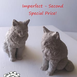 May include: Two gray cat sculptures, handmade by Wire Animals USA, sit side-by-side. The text "Imperfect - Second Special Price!" is written in red above the cats. The sculptures are detailed with textured fur and seated poses.