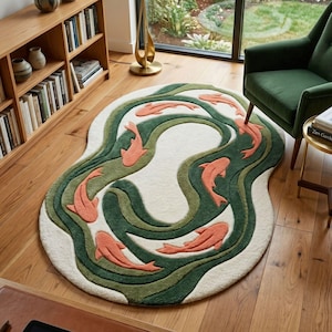 Puede incluir: Una alfombra redonda con un centro color crema y un diseño de líneas onduladas verdes y oliva. Peces de color salmón están dispersos por todo el diseño. La alfombra está colocada sobre un suelo de madera.