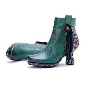 May include: A pair of emerald green ankle boots featuring dark green leather with decorative stitching, brass-toned studs along the base, a side tassel detail with a circular accent, and a patterned heel with blue, pink, and black floral motifs.