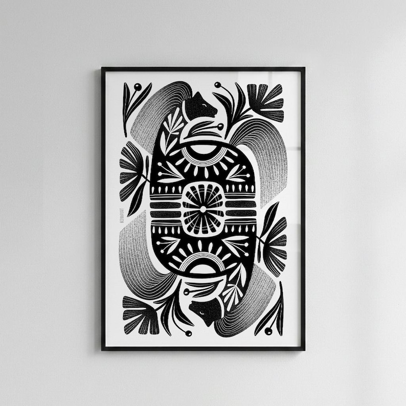 May include: Black and white framed art print featuring a symmetrical design. The artwork includes stylized floral and animal motifs, with intricate patterns and details. The print is set against a white background.
