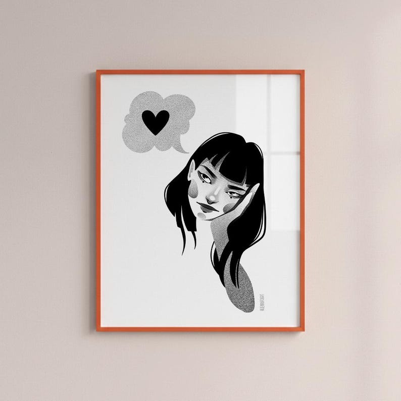 May include: A framed black and white illustration of a woman with black hair and a thought bubble with a heart. The artwork has a minimalist style and is framed in an orange frame.