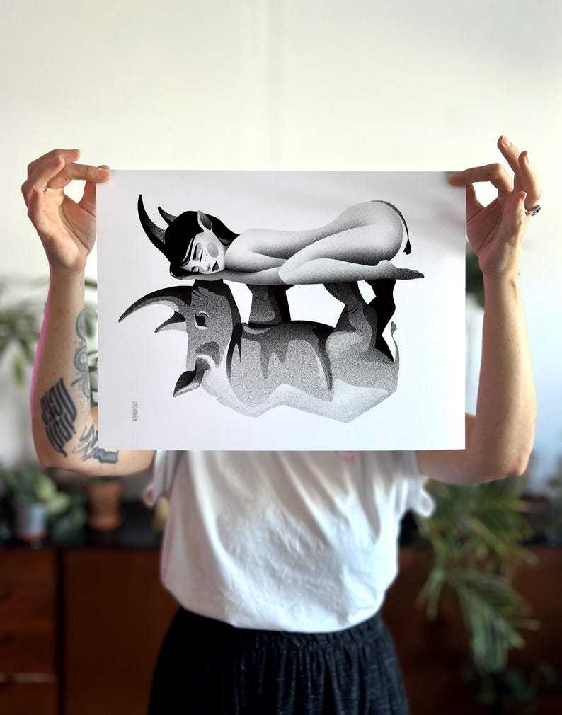 Może przedstawiać: Czarno-biały wydruk artystyczny przedstawiający leżącą postać z rogami na byczej formie. Grafika ma szczeg&oacute;łową, kropkowaną fakturę, tworząc obraz w skali szarości. Wydruk jest trzymany przez osobę.