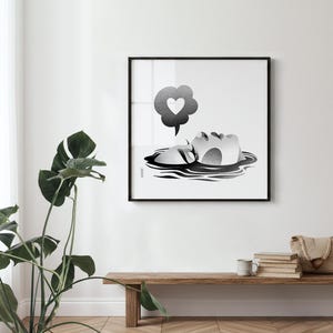 K&ouml;nnte beinhalten: Schwarz-Wei&szlig;-Kunstdruck einer Person, die im Wasser schwimmt, mit einer Sprechblase mit einem Herzen. Das Kunstwerk ist in einem schwarzen quadratischen Rahmen an einer wei&szlig;en Wand gerahmt. Eine Holzbank und eine Topfpflanze befinden sich im Vordergrund.