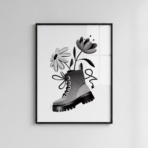 May include: A black and white digital art print featuring a stippled illustration of a lace-up combat boot with a thick lug sole. Two stylized flowers emerge from the top of the boot, with long laces extending outward in a decorative loop.