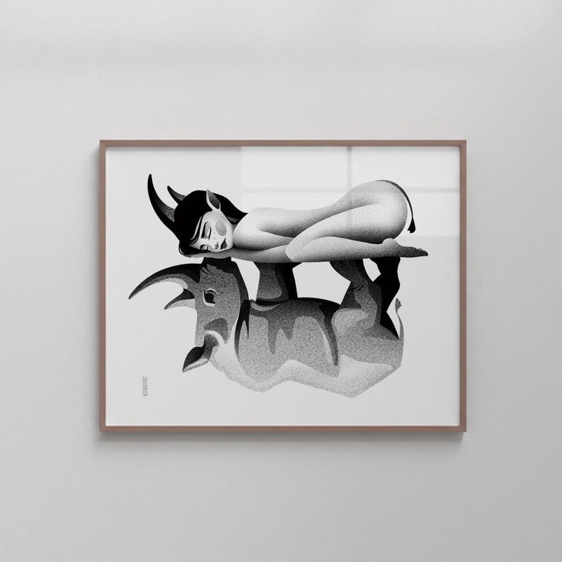 Może przedstawiać: Czarno-biały wydruk artystyczny przedstawiający kobietę z rogami leżącą na byku. Grafika jest oprawiona w brązową ramę i eksponowana na białej ścianie. Obraz ma minimalistyczny styl.