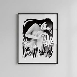 以下が含まれることがあります： 長い髪の女性が、様式化された花や葉の中に座っている白黒のアートプリント。アートワークは黒い縁で額装されており、印象的なコントラストを生み出しています。イラストは柔らかく、夢のような雰囲気です。