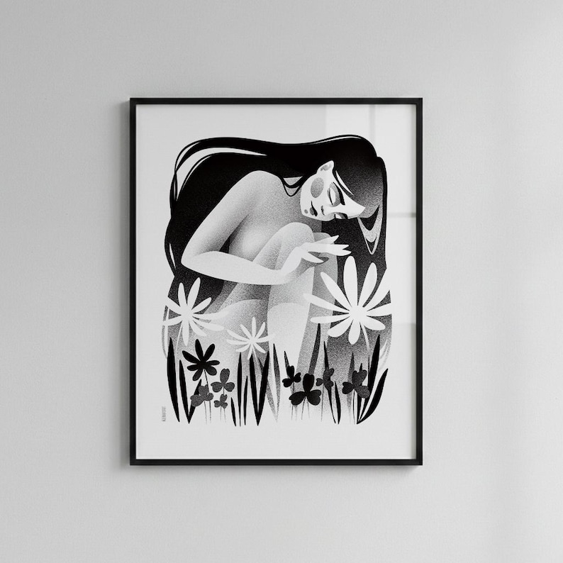 以下が含まれることがあります： 長い髪の女性が、様式化された花や葉の中に座っている白黒のアートプリント。アートワークは黒い縁で額装されており、印象的なコントラストを生み出しています。イラストは柔らかく、夢のような雰囲気です。