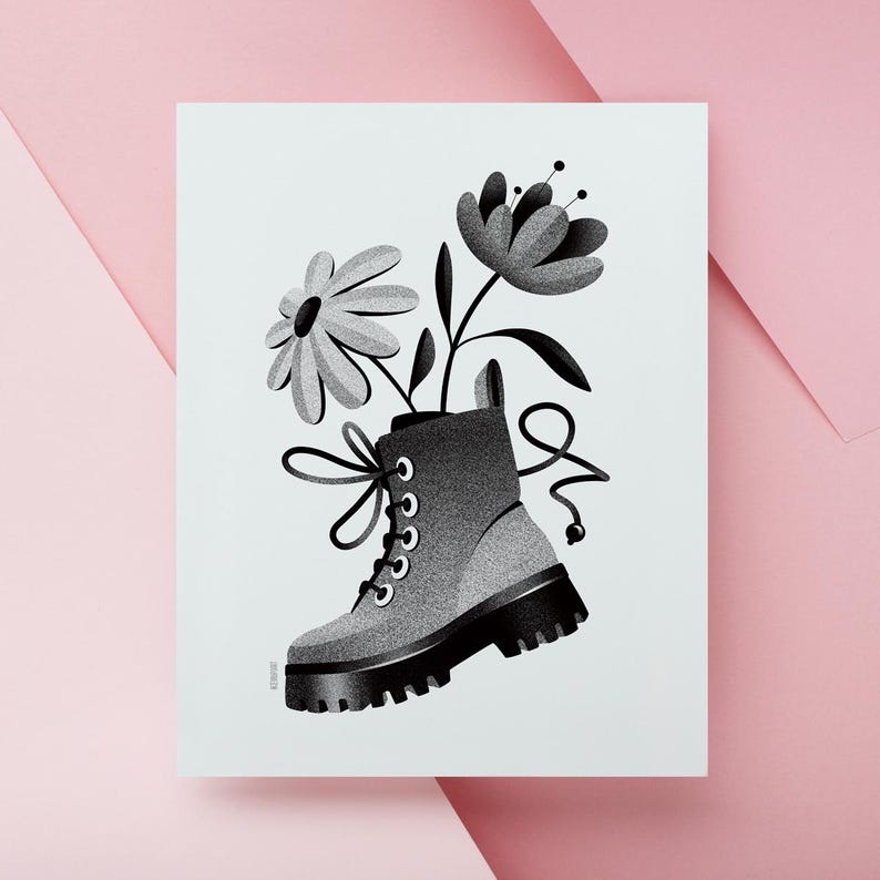 May include: Black and white illustration of a combat boot with flowers growing out of it. The boot is gray with black laces and a thick black sole. Two flowers with black stems and leaves are coming out of the boot. The background is white with a pink border.