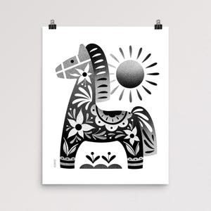 以下が含まれることがあります： 花と葉のモチーフが施された装飾的な馬を描いた白黒のアートプリント。背景には太陽のイラストがあります。馬のデザインはフォークアートスタイルです。