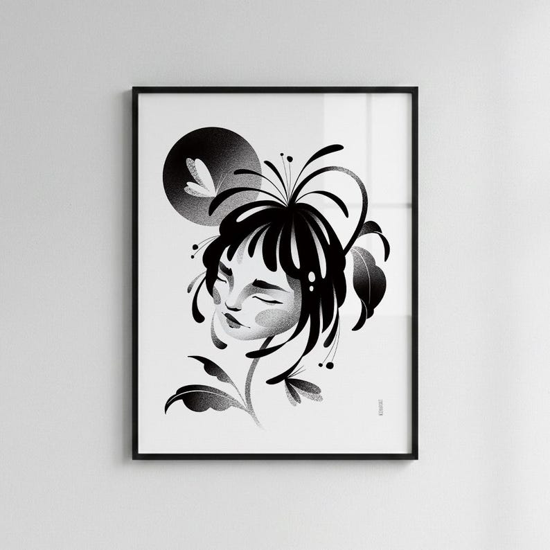 May include: A black and white framed art print featuring a stylized illustration of a person with closed eyes, surrounded by flowing hair and botanical elements. A dark circular shape sits in the upper left corner, and the artwork is enclosed in a thin black frame.