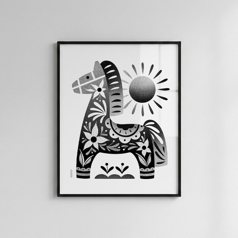 以下が含まれることがあります： 花柄と太陽が描かれた、白黒の額入りアートプリント。馬は花やその他のデザインで装飾されています。太陽からは光線が出ています。アートワークは黒いフレームに入っています。