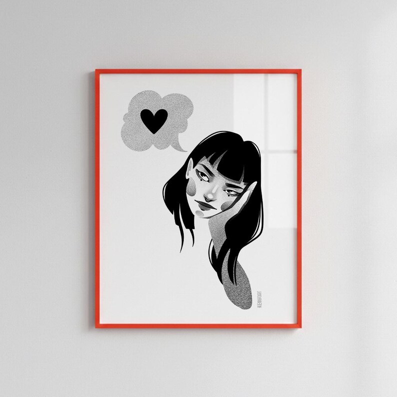 May include: A framed art print featuring a black and white illustration of a woman with black hair, resting her head on her hand. A thought bubble with a black heart floats above her head. The frame is red.