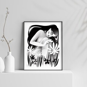 以下が含まれることがあります： 長い髪の女性が様式化された花の中に座っている白黒のアートプリント。アートワークは額装され、白い表面に展示されており、近くには装飾用の白い花瓶と花の小枝があります。