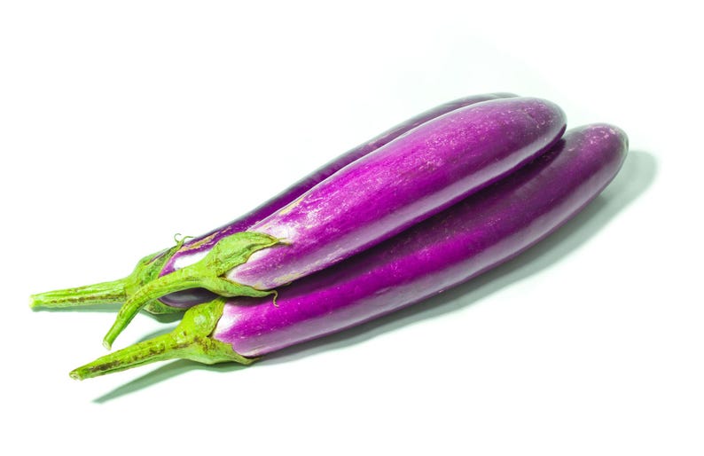 Op de afbeelding: Drie lange, slanke aubergines met een gladde, glanzende, dieppaarse schil en felgroene kelkbladeren aan de steelaanzet. De groenten zijn in een groepje gerangschikt en tonen hun langwerpige, cilindrische vorm en egale paarse kleur.