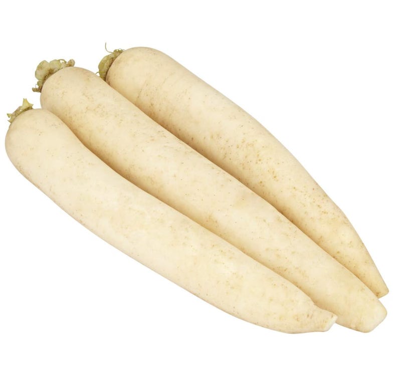 Op de afbeelding: Drie lange, cilindervormige daikon-radijzen met een gladde, gebroken witte schil en subtiele lichtbruine spikkels. Elke groente heeft een taps toelopend uiteinde en een klein, lichtgroen steeltje aan de bovenkant, diagonaal gerangschikt.