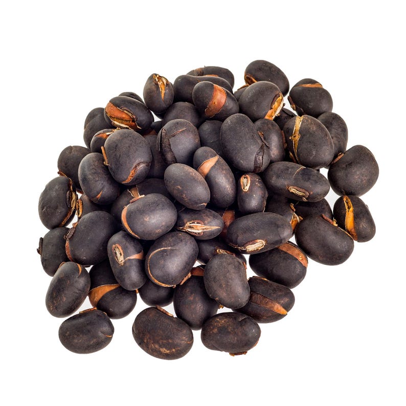 Puede incluir: Un grupo de frijoles secos de color marr&oacute;n oscuro a negro con superficies lisas y ovaladas. Cada frijol presenta un hilio o cicatriz de color tostado claro donde estaba unido a la vaina, creando un contraste visible con la piel oscura.