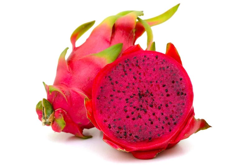 May include: A whole dragon fruit with vibrant pink skin and green-tipped scales positioned next to a halved dragon fruit, revealing a deep magenta flesh speckled with numerous tiny black seeds, all set against a plain white background.