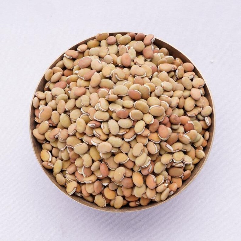 Puede incluir: Un cuenco met&aacute;lico redondo lleno de una gran cantidad de frijoles secos de forma ovalada. Los frijoles presentan una variedad de tonos tierra, que van desde el beige claro y el bronceado hasta el marr&oacute;n rojizo, cada uno con una l&iacute;nea blanca.