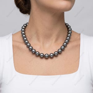 May include: A necklace of dark grey pearls. The necklace is made up of many round, uniformly sized pearls. The pearls are strung together, creating a full circle around the neck. The background is plain white.